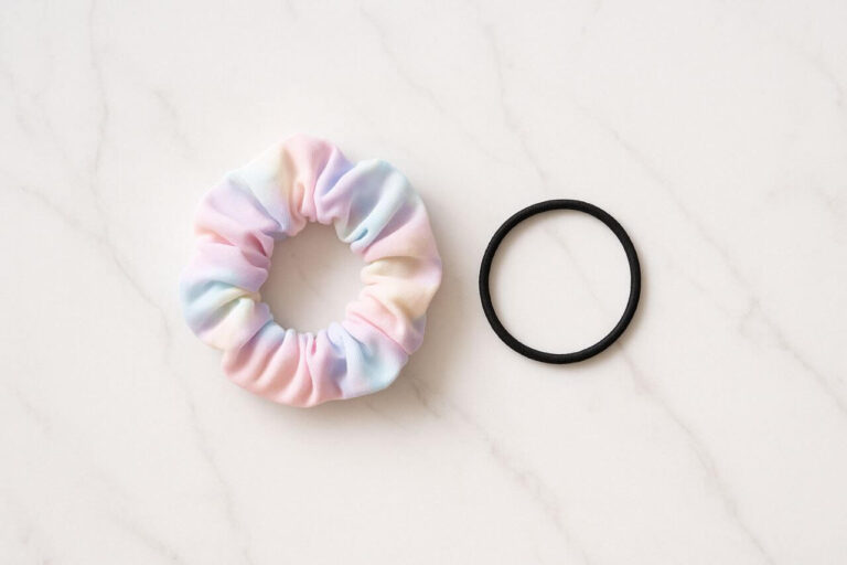 Pastel scrunchie and black hair tie comparison on marble surface"